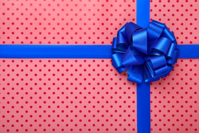 Photo of Blue ribbons with bow on red polka dot wrapping paper, top view
