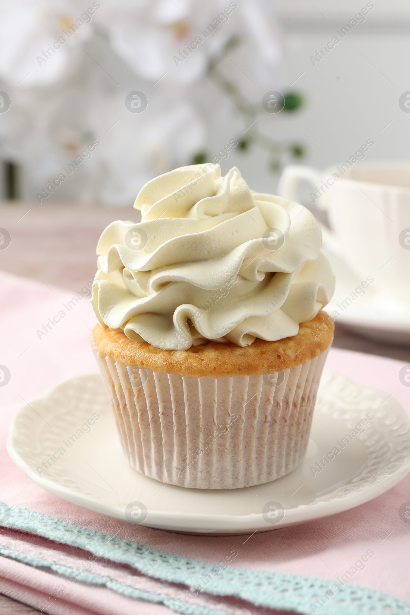 Photo of Tasty cupcake with vanilla cream on table, closeup