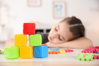 Photo of Little girl with autistic disorder playing at home, closeup of cubes
