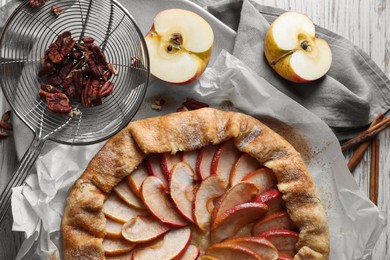 Delicious apple galette, cinnamon and pecans on table, flat lay