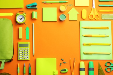 Frame of different bright school stationery on orange background, flat lay. Space for text