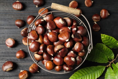 Fresh sweet edible chestnuts on black wooden  table, flat lay