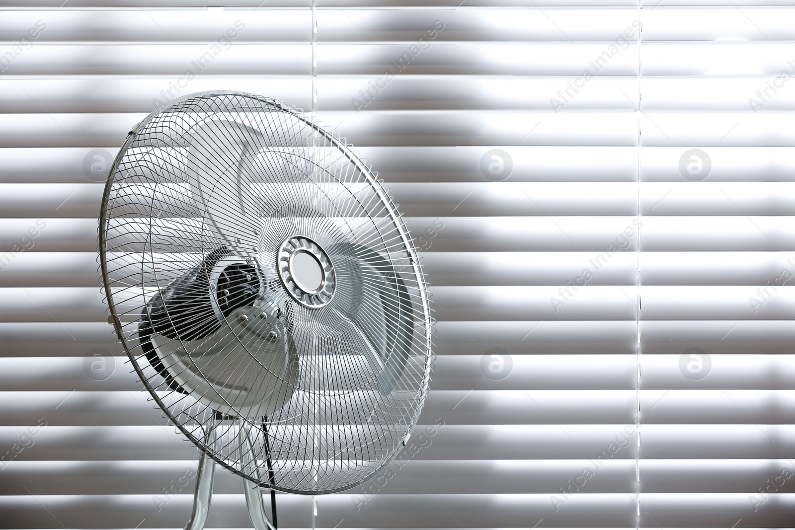 Photo of Modern electric fan near window indoors. Space for text