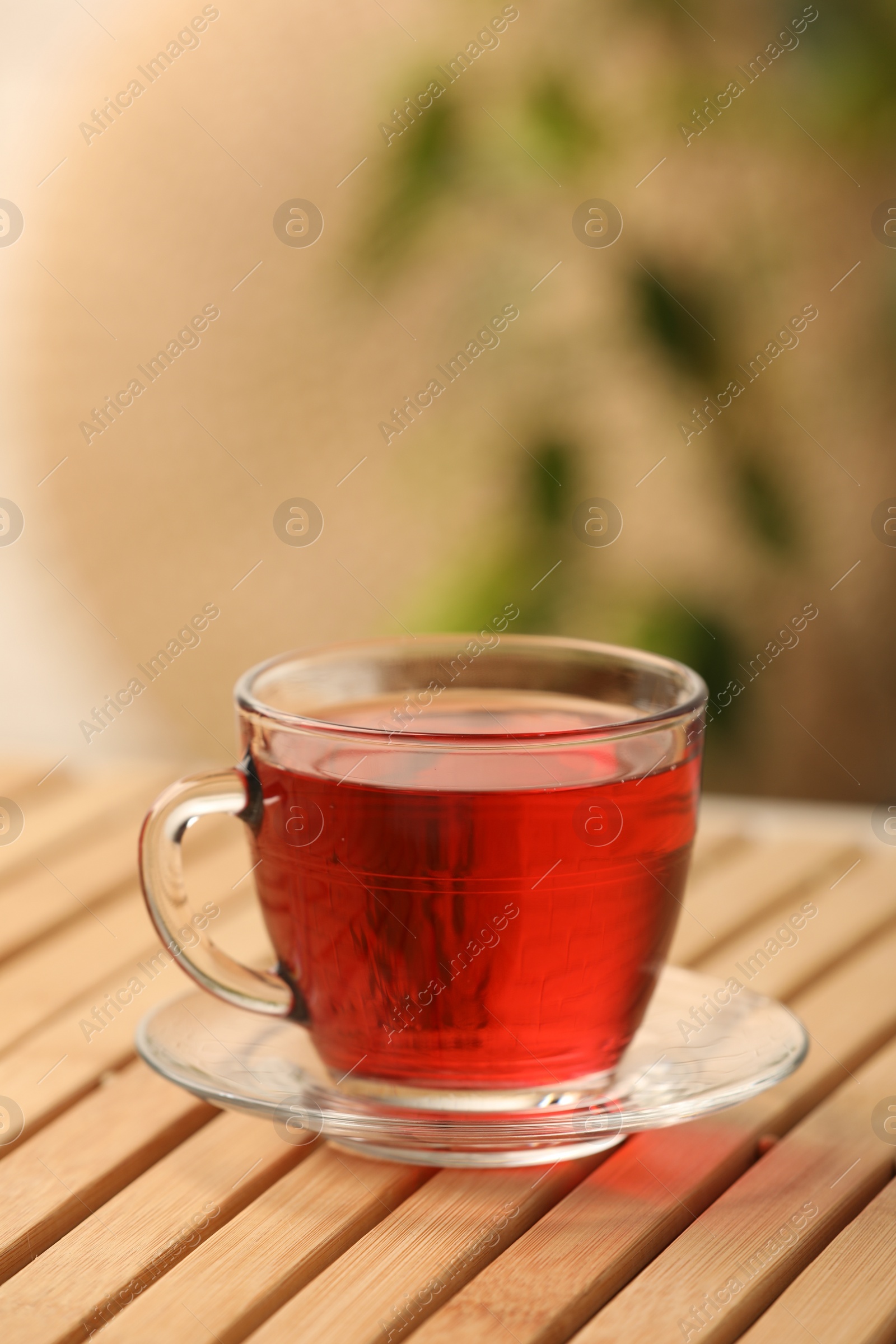 Photo of Cup of delicious hibiscus tea on wooden table, space for text