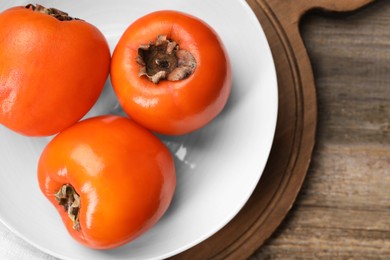 Photo of Delicious ripe persimmons on wooden table, top view