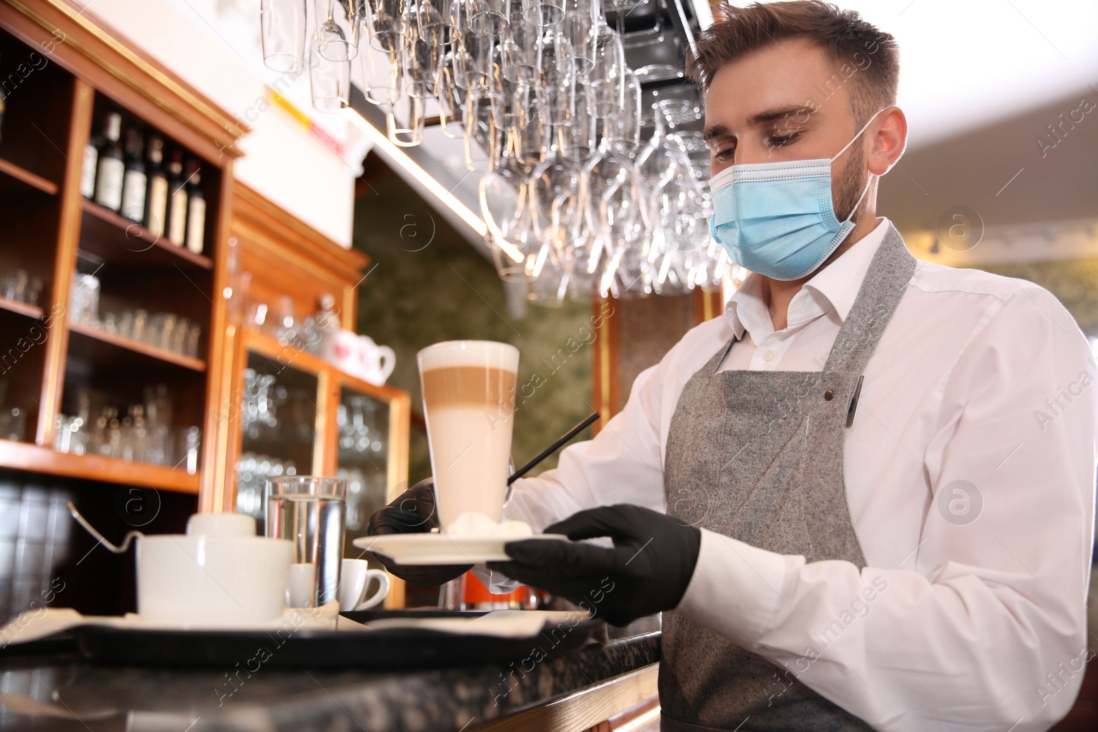 Photo of Waiter serving beverages in restaurant. Catering during coronavirus quarantine