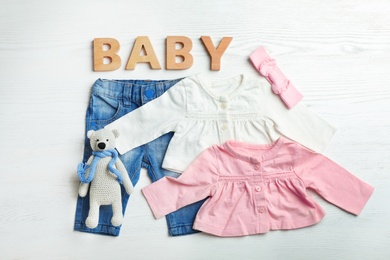 Photo of Flat lay composition with cute clothes on white wooden background. Baby accessories