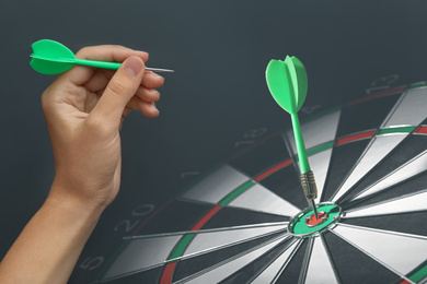 Image of Woman with darts and board on grey background, closeup