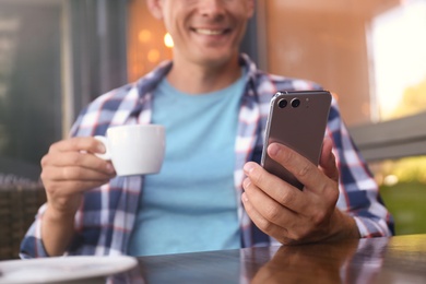 Man with smartphone in outdoor cafe, closeup