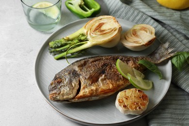 Delicious dorado fish with vegetables served on light grey table