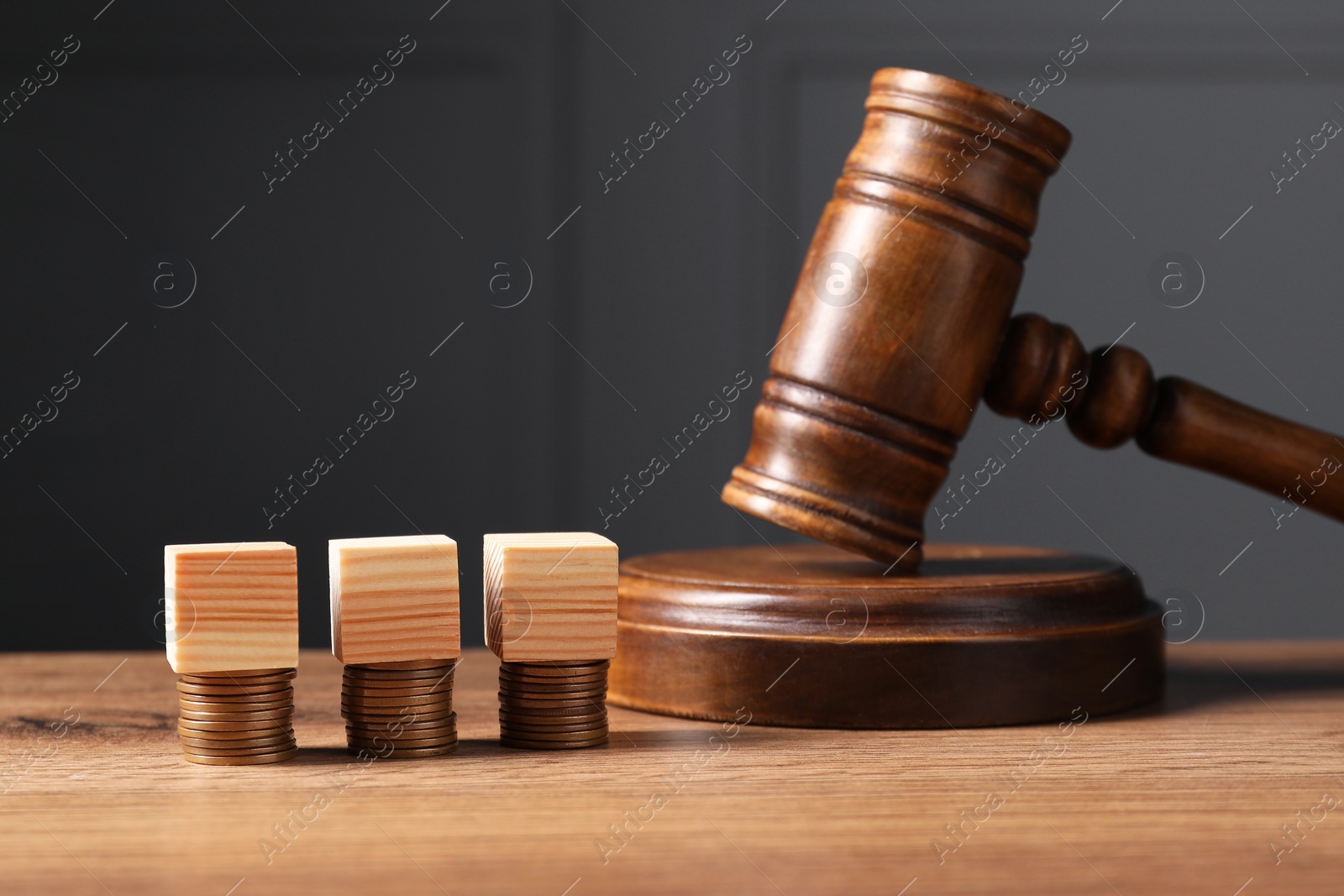 Photo of Tax law. Blank wooden cubes, stacked coins and gavel on table