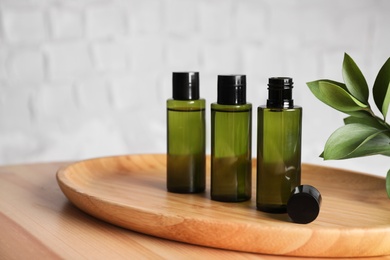 Mini bottles with cosmetic products on wooden table against white background. Space for text