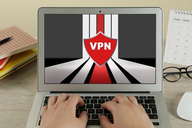 Image of Woman using laptop with switched on VPN at wooden table, closeup
