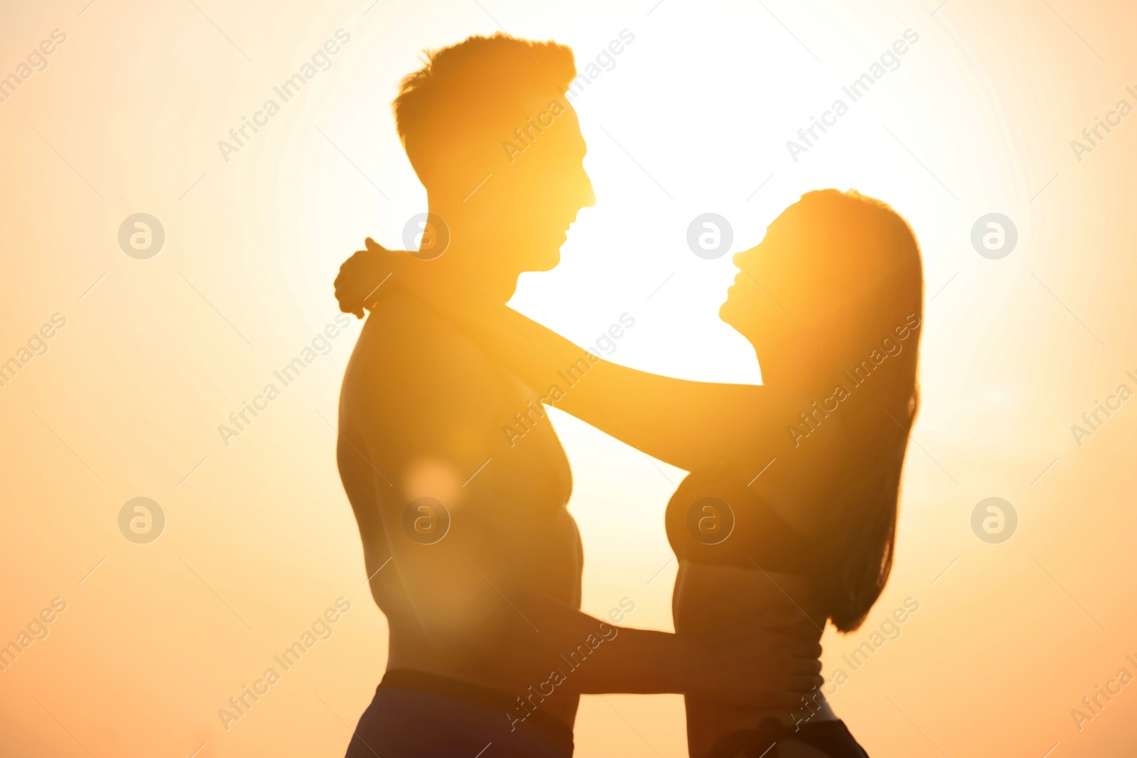 Photo of Young woman in bikini spending time with her boyfriend outdoors at sunset. Lovely couple