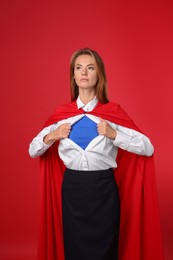 Photo of Confident businesswoman wearing superhero costume under suit on red background