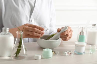 Scientist making cosmetic product at table in laboratory, closeup