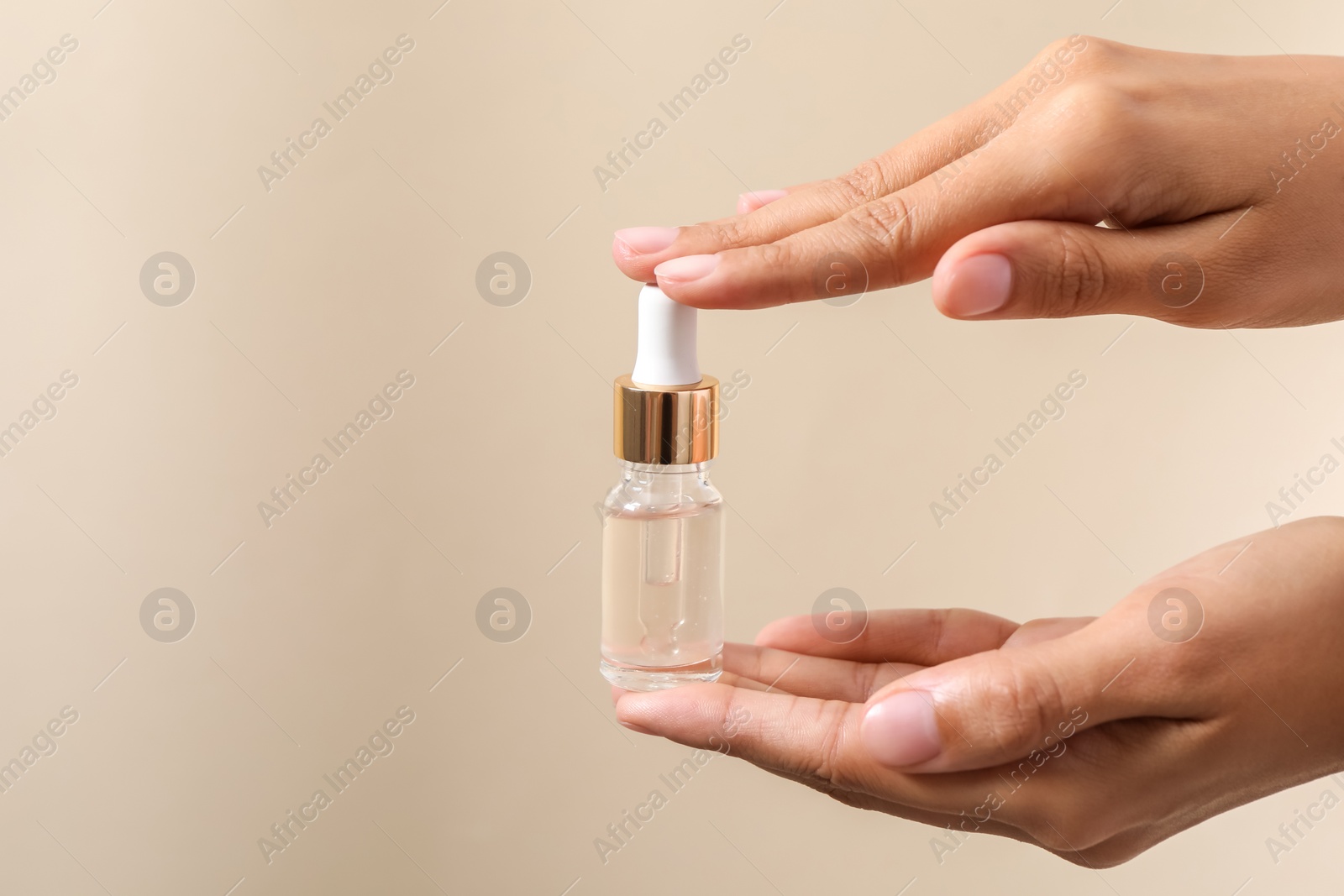 Photo of Woman with bottle of cosmetic serum on beige background, closeup. Space for text