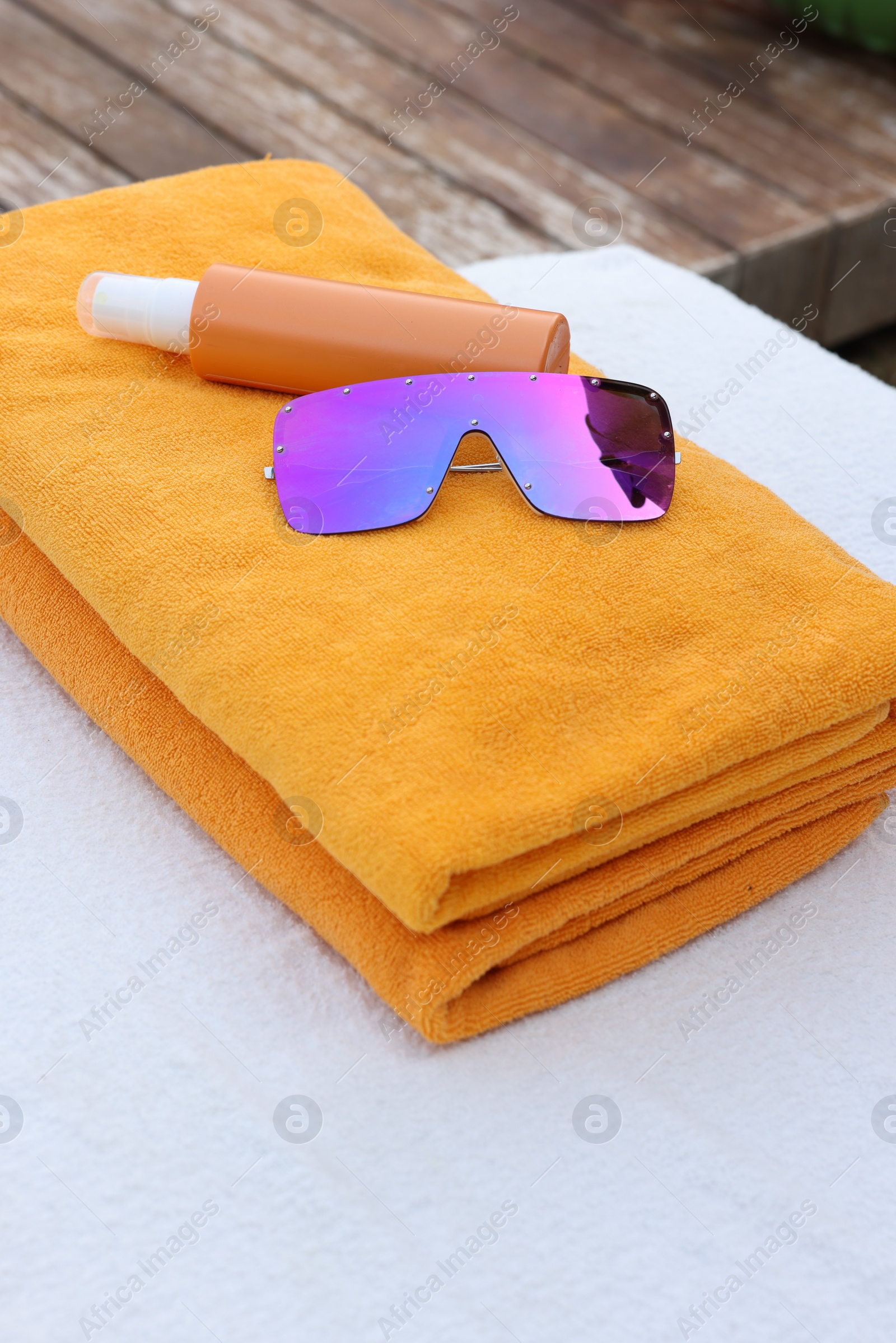 Photo of Beach towels, sunglasses and sunscreen on sunbed at resort