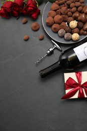 Photo of Red wine, chocolate truffles, gift box, roses and corkscrew on gray table, flat lay. Space for text