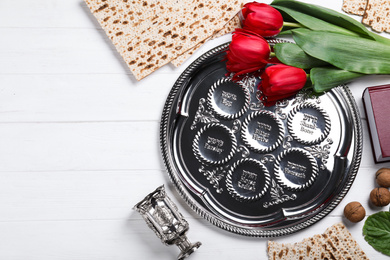 Photo of Flat lay composition with Passover Seder plate (keara) on white wooden table. Pesah celebration