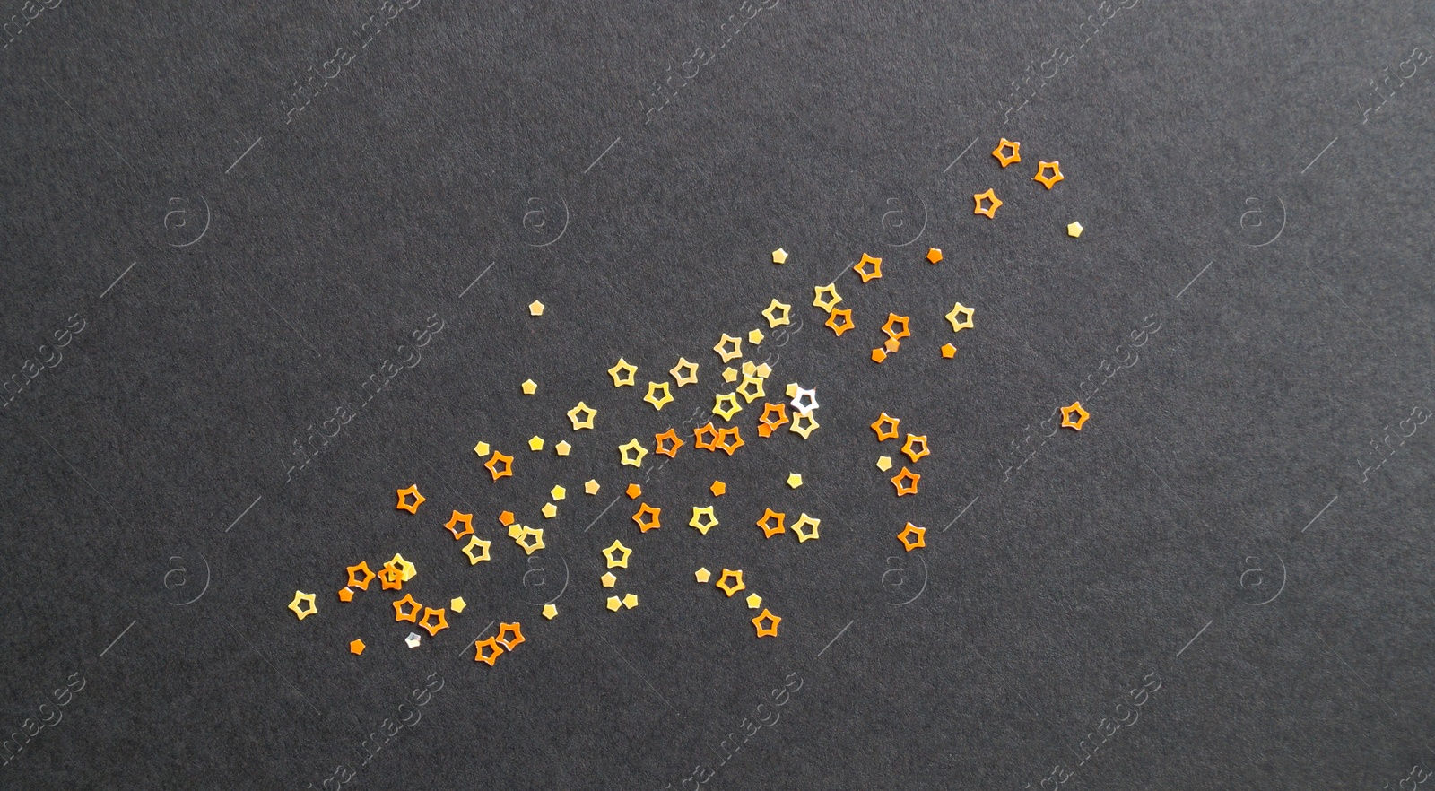 Photo of Many beautiful star shaped sequins on black background, flat lay