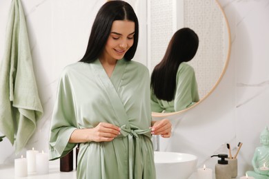 Photo of Beautiful young woman near mirror in bathroom