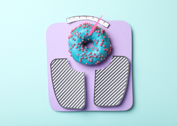 Photo of Scales made with donut and paper on light blue background, top view