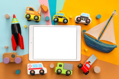 Photo of Modern tablet and toys on color background, flat lay. Space for text