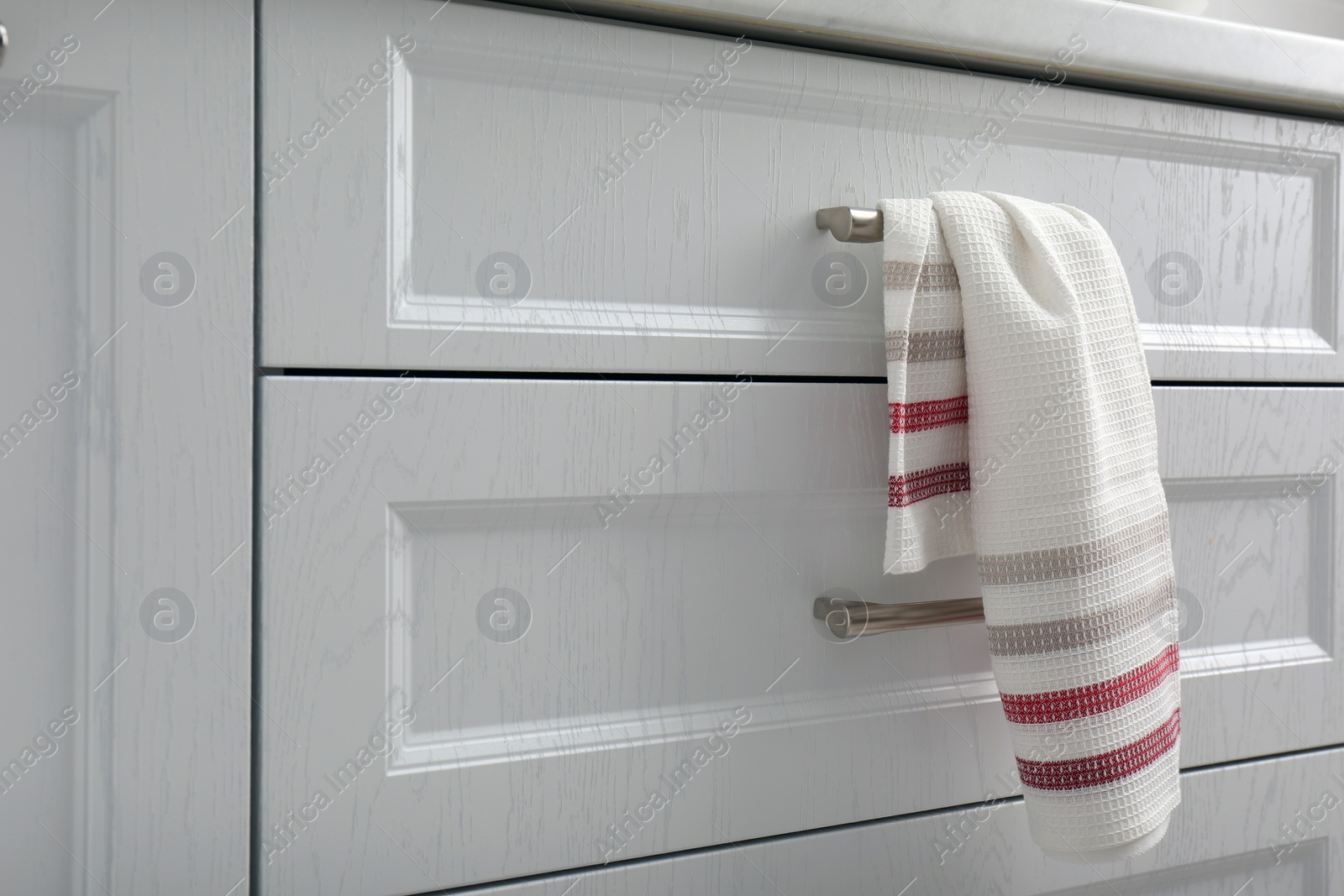 Photo of Soft kitchen towel hanging on drawer handle indoors