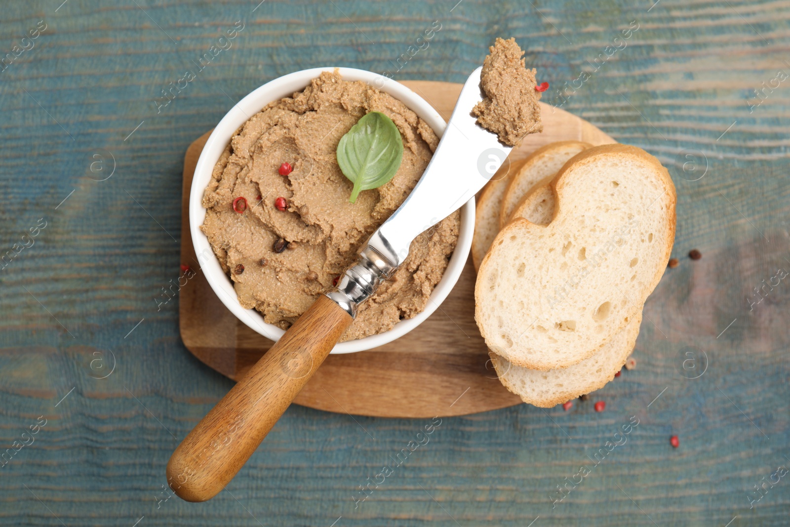 Photo of Delicious meat pate with spices, fresh bread and knife on blue wooden table, flat lay