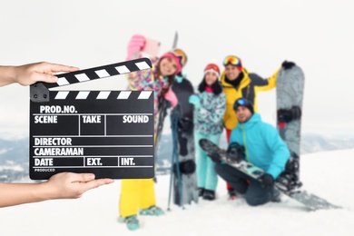 Image of Assistant  holding clapperboard and people in snowy mountains, closeup. Cinema production 