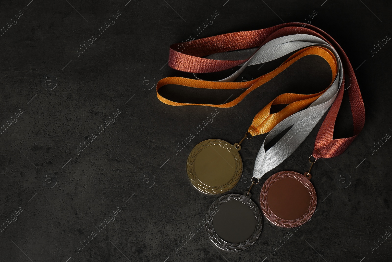 Photo of Gold, silver and bronze medals on grey stone background, flat lay. Space for design