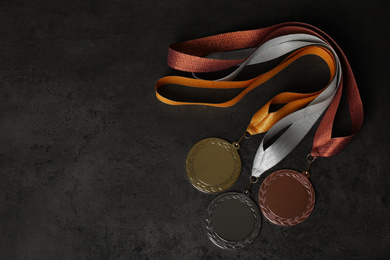 Gold, silver and bronze medals on grey stone background, flat lay. Space for design