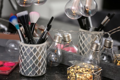 Holder with professional brushes on dressing table in makeup room