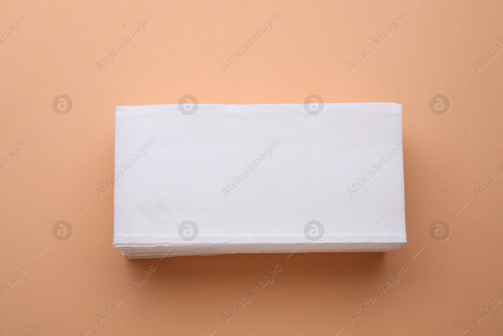 Photo of Stack of clean tissue towels on beige background, top view