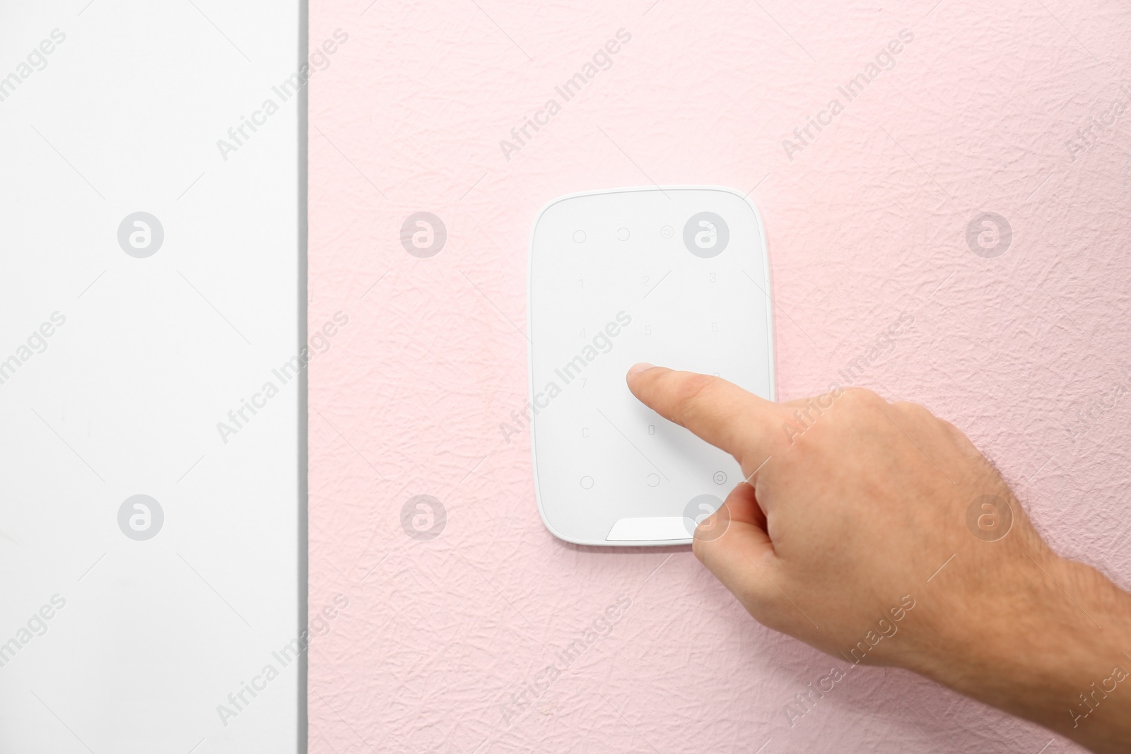 Image of Young man entering code on alarm system keypad indoors, closeup