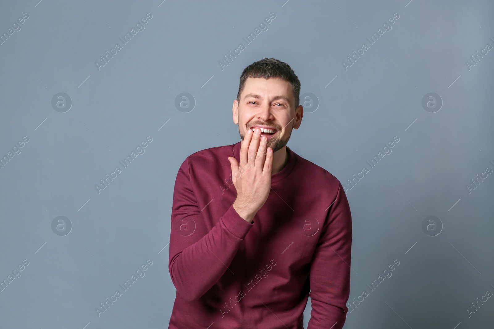 Photo of Handsome man laughing on grey background. Funny joke