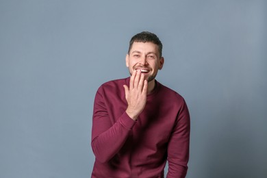Photo of Handsome man laughing on grey background. Funny joke