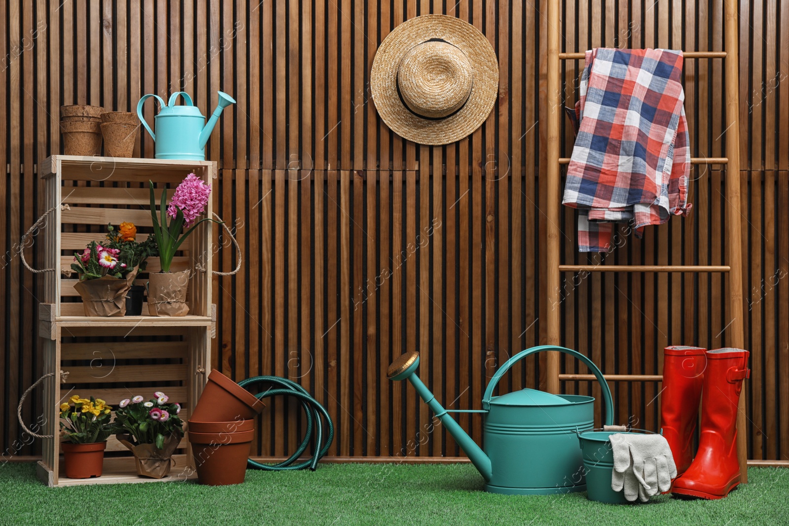 Photo of Composition with different gardening tools on artificial grass at wooden wall. Space for text