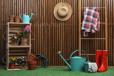 Composition with different gardening tools on artificial grass at wooden wall. Space for text