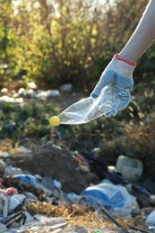 Photo of Woman picking up plastic garbage outdoors, closeup