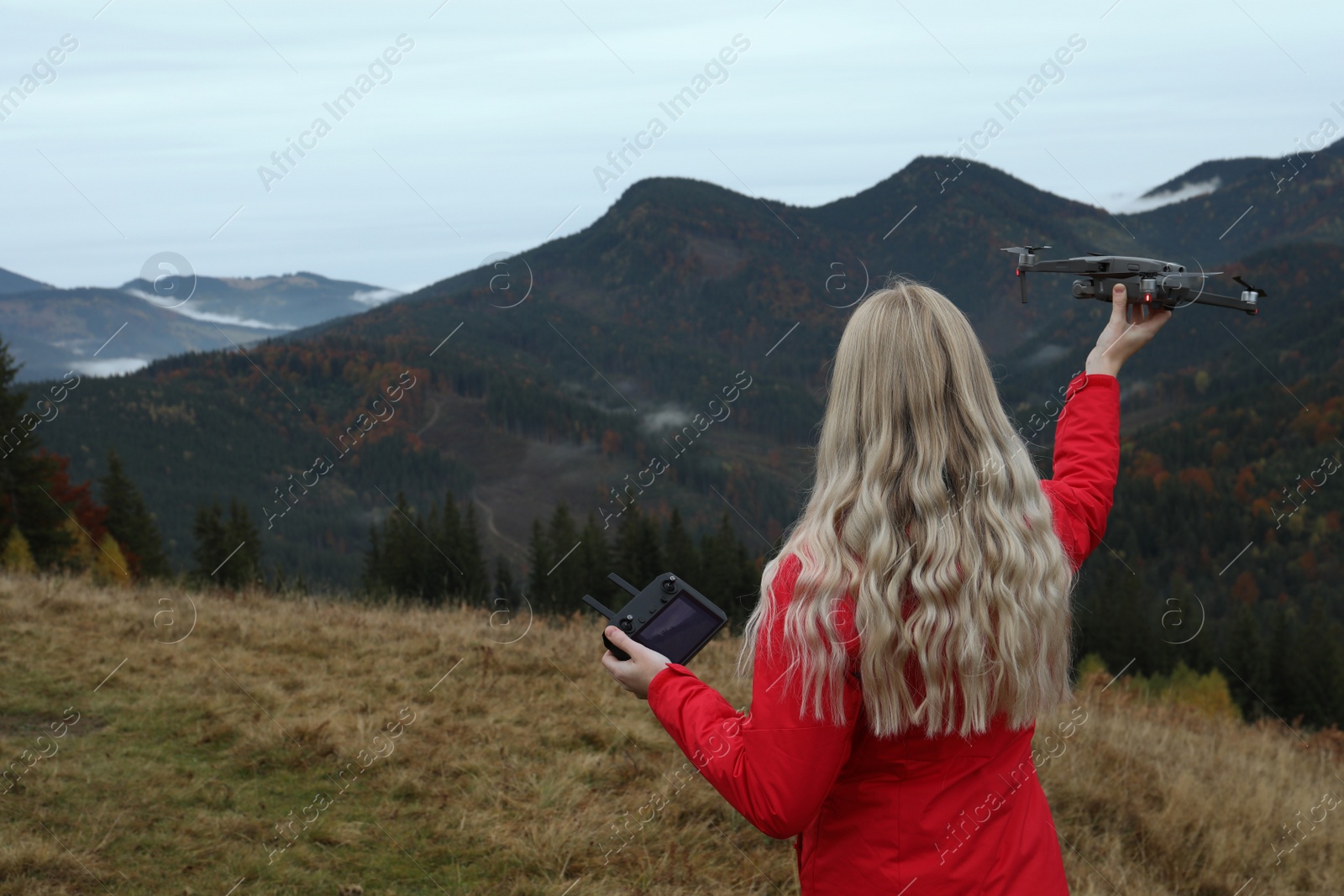 Photo of Young woman with modern drone in mountains, back view. Space for text