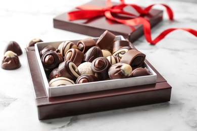 Box with different tasty chocolate candies on table