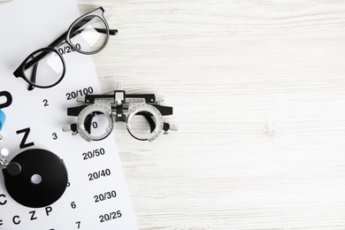 Different ophthalmologist tools on white wooden background, flat lay. Space for text