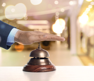 Man ringing hotel service bell on blurred background, closeup
