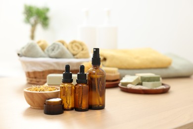 Photo of Bottles of essential oils, dry flowers and jar with cream on light wooden table, space for text. Spa therapy