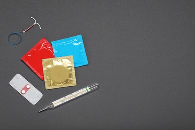 Photo of Contraceptive pills, condoms, intrauterine device and thermometer on grey background, flat lay and space for text. Different birth control methods