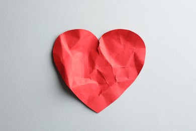 Photo of Crumpled red paper heart on white background, top view. Broken heart