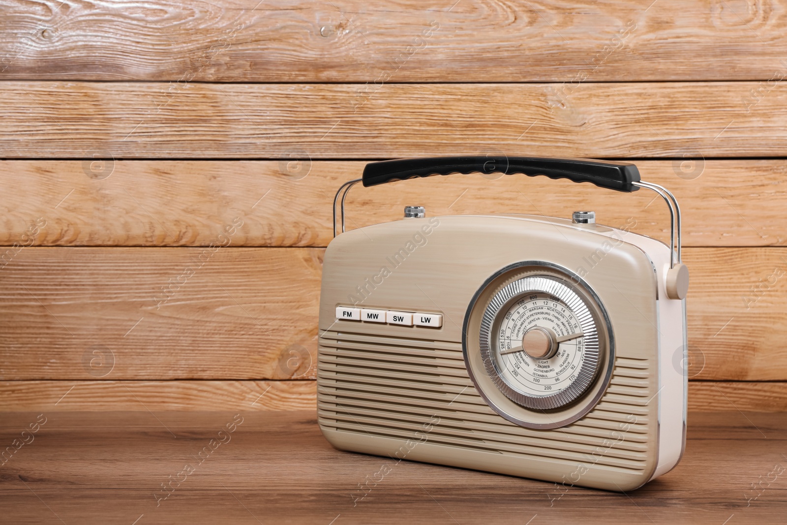 Photo of Retro radio receiver on table against wooden background. Space for text