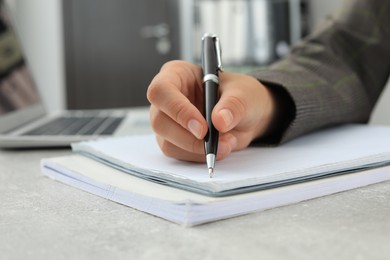 Photo of Woman writing in notebook at table indoors, closeup